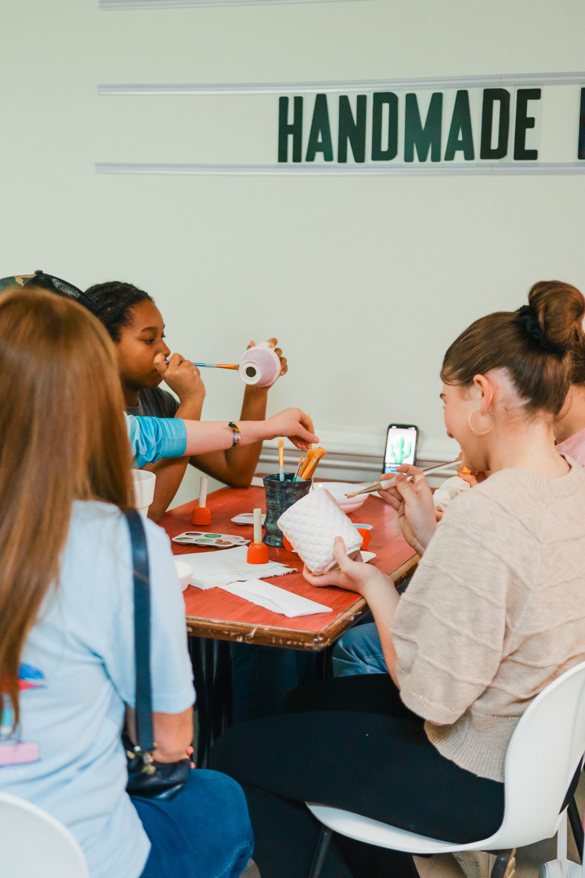 Friends painting pottery together and laughing