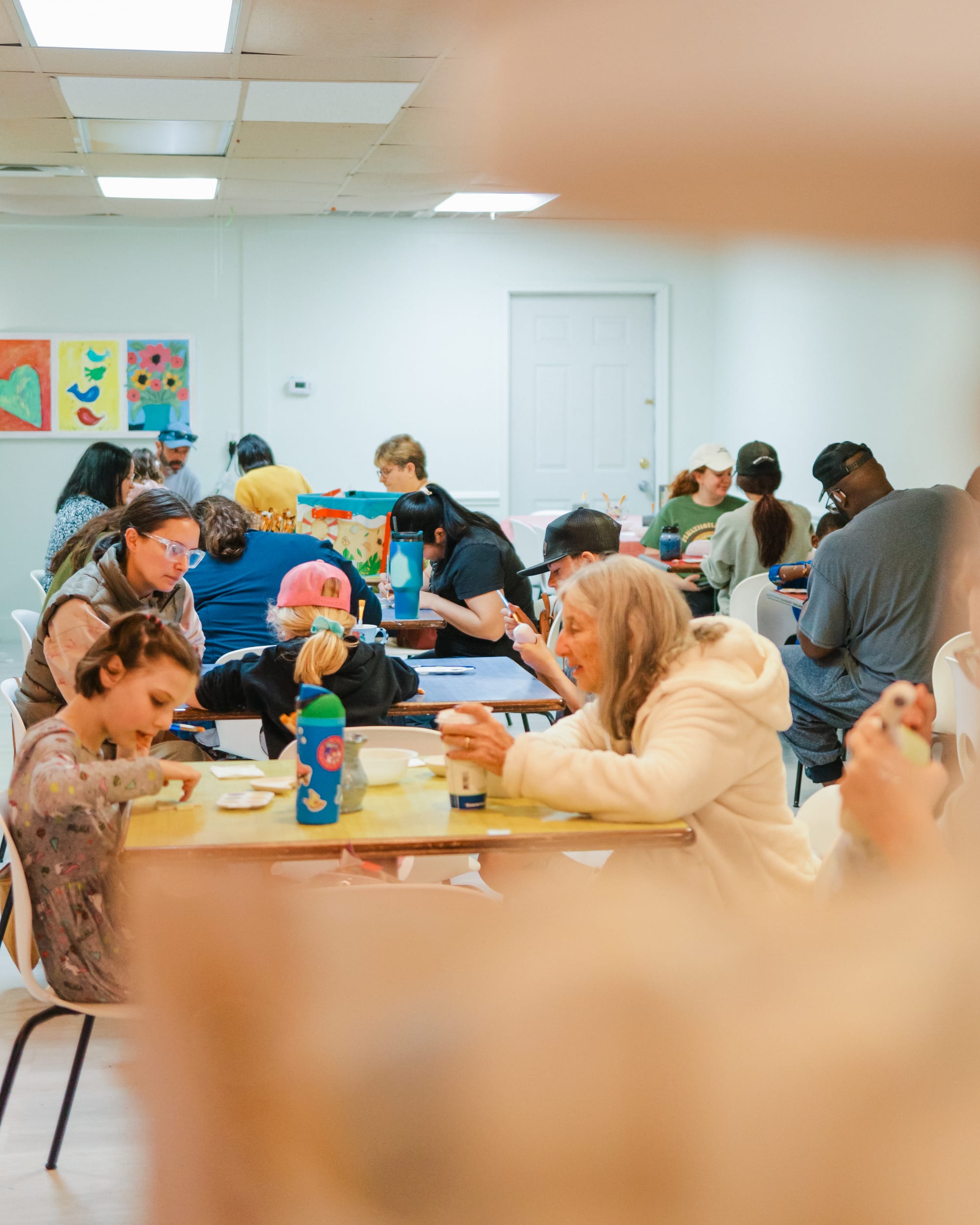 A family laughing together while painting pottery at Artsy Me